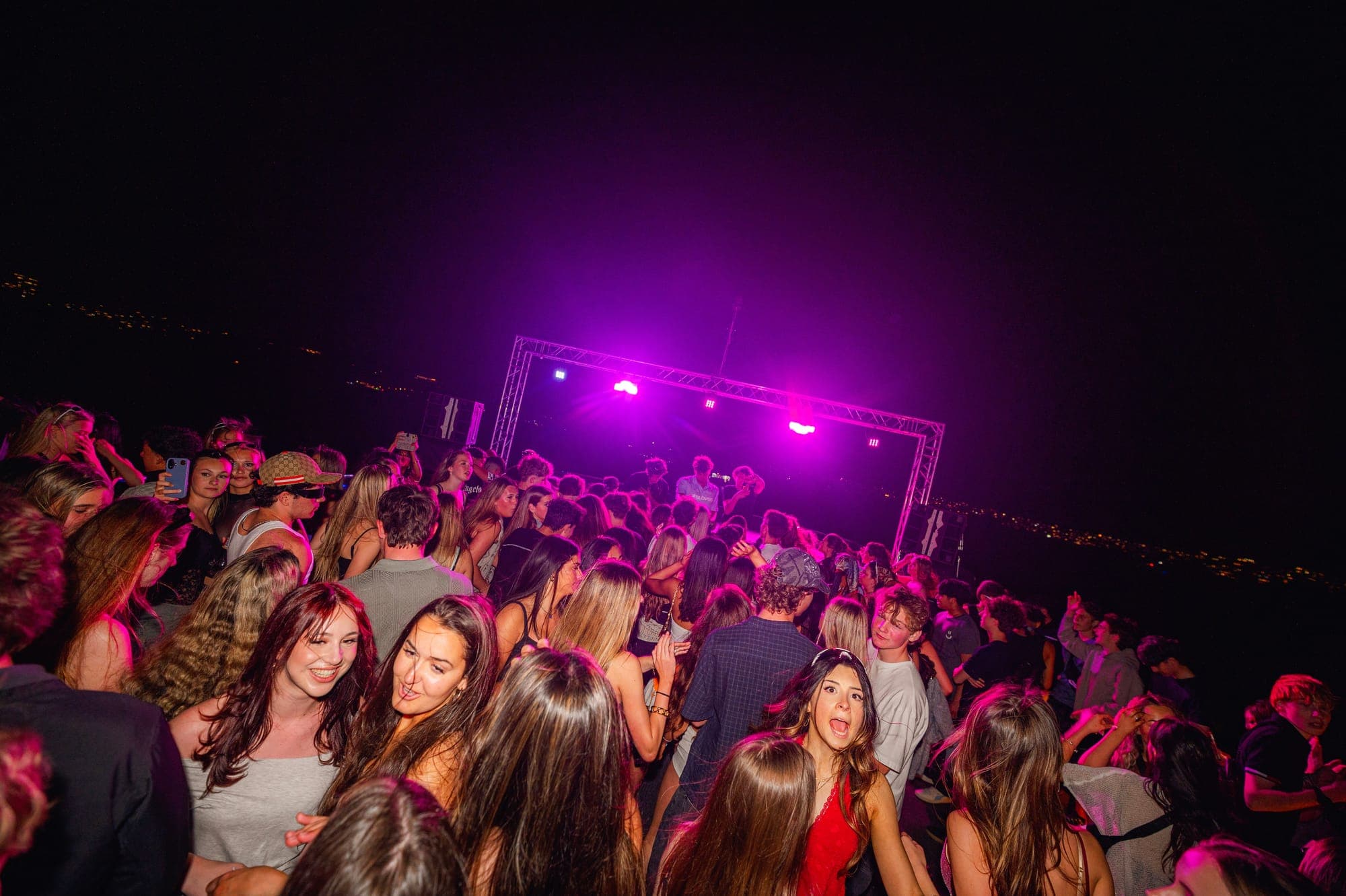 Open-air boat dancefloor with pink stage lights and the harbour beyond